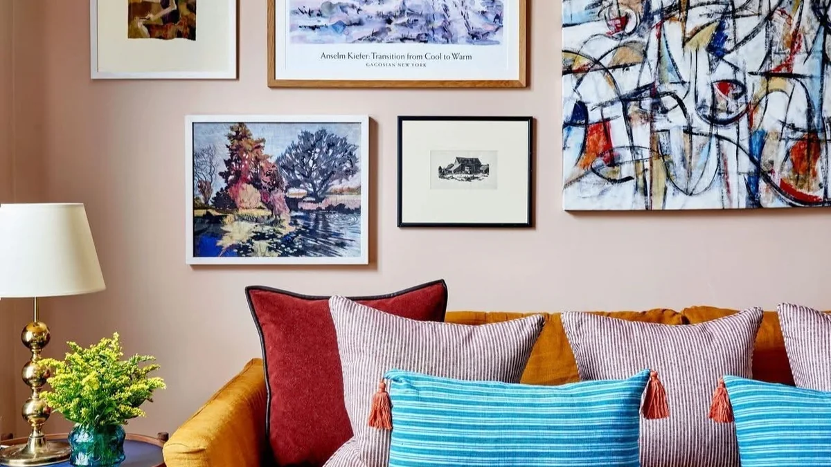 Colourful living room with collected art above a mustard sofa