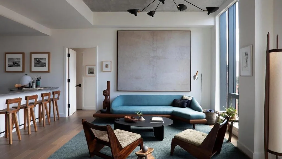 Calm modern living room with a blue sofa beside tall windows